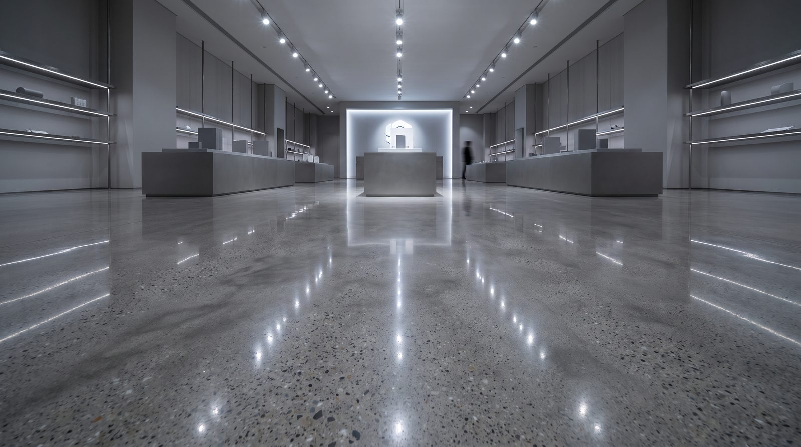 Showroom mağazada ürün podyumlarını ve tavan spot ışıklarını yansıtan süper parlak parlatılmış beton sergileme zemini.